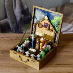 an open wooden box with nativity figurines in it on a wood table