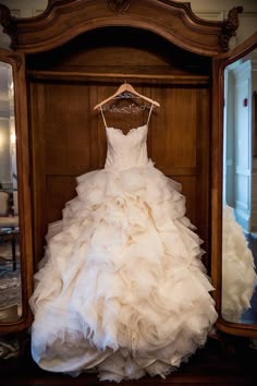 a wedding dress hanging in front of a mirror