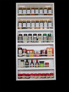 an organized spice rack with spices and condiments in white painted shelving unit