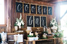 a table topped with lots of food next to a wall covered in chalkboard signs