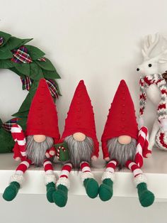 three christmas gnomes are sitting on a mantle