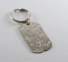 a metal keychain that has various symbols on it and is sitting on a white surface