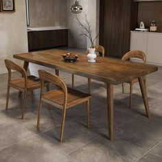 a dining room table with chairs and a vase on the top, in front of an open kitchen area