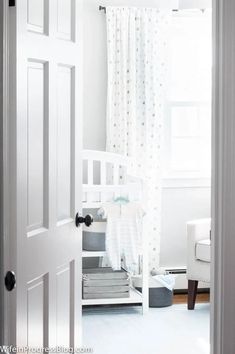 a baby's room with white walls and curtains