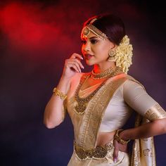 a woman in a white and gold sari with her hands on her hip, posing for the camera