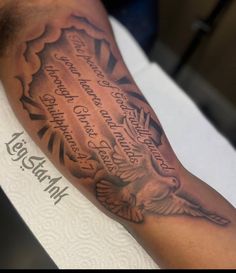 a man's arm with an eagle and bible verse tattoo on it, sitting on top of a table