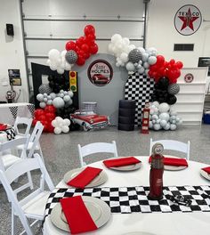 a table set up for a party with red, white and black balloons in the background