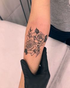 a woman's arm with a rose tattoo on her left arm and black gloves