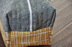 a gray and yellow bag sitting on top of a wooden floor