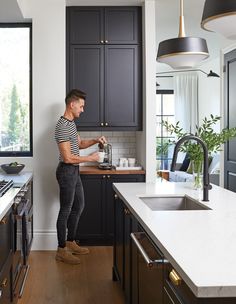 a man standing in a kitchen next to a sink