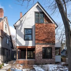 a two story house with wood shingles on the front and side of it in winter