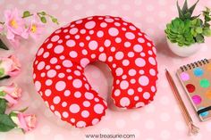 a red and white polka dot donut pillow next to a notebook, potted plant and pen