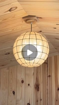 a light fixture hanging from the ceiling in a room with wood paneling and wooden walls