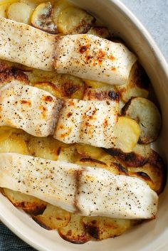 fish and potatoes in a white dish with seasoning on the top, ready to be eaten