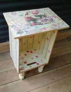 a wooden box with flowers painted on it sitting on top of a wooden floor next to a wall