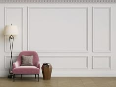 a pink chair sitting next to a lamp on top of a hard wood floor in front of a white wall