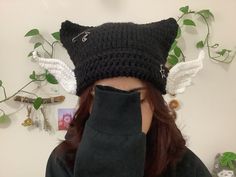 a woman with red hair wearing a black knitted cat hat and fingerless gloves