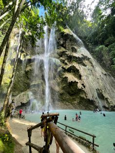 people are standing in front of a waterfall with water cascading down it's side