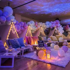 a room filled with lots of balloons and lights on the ceiling, next to a couch