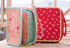 three purses sitting on top of a wooden table next to each other in front of a window