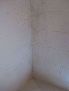 the corner of a room with white walls and dirt all over it's surface