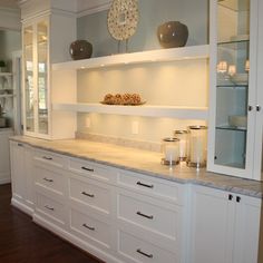 a kitchen with white cabinets and marble counter tops