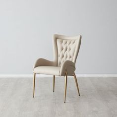 a beige chair sitting on top of a hard wood floor next to a white wall