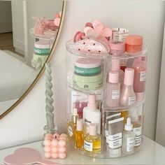 a clear container filled with lots of beauty products on top of a white table next to a mirror