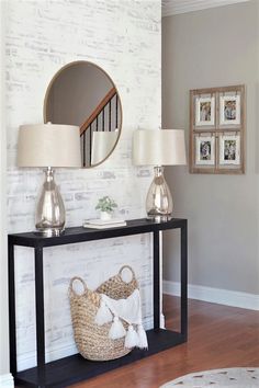 a table with two lamps and a basket on it in front of a white brick wall