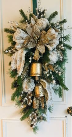 a christmas wreath hanging on the door with bells and pine cones in front of it