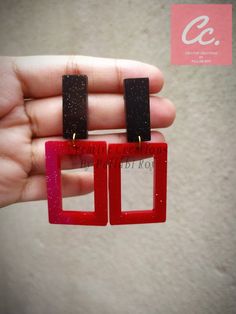 a pair of red and black square shaped earrings in the shape of rectangles