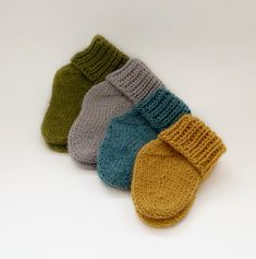 three pairs of knitted mittens sitting on top of each other in different colors