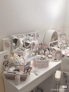 a white desk topped with lots of different types of items next to a chair and mirror