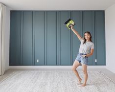 a woman holding a drill and a tool in her hand while standing on the floor