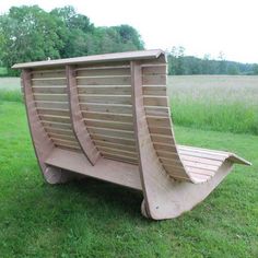 a wooden bench sitting on top of a lush green field next to tall grass and trees