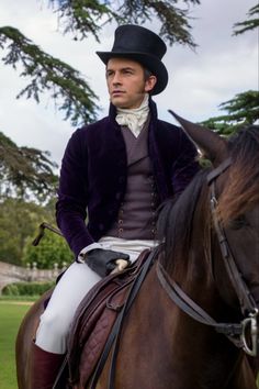 a man riding on the back of a brown horse wearing a top hat and purple jacket