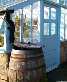 an old wooden barrel sitting in front of a building with potted plants on it