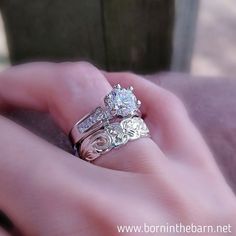 a woman's hand holding two wedding rings with diamond accents on each ring and an engagement band