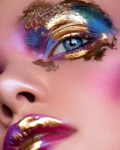 a woman's face with gold and blue makeup