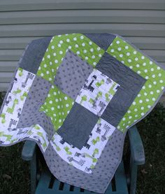 a green and gray quilt sitting on top of a wooden chair in front of a house