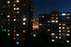 some buildings are lit up at night with the lights turned on and windows glowing brightly