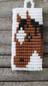 a beaded dog ornament hanging on a wooden surface with wood planks