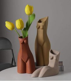 three vases sitting on top of a table with yellow flowers in them and an elephant statue next to it