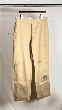 An authentic vintage pair of twill chino trouser pants. US military issued. four pocket style. zip fly. regular relaxed fit. wide straight leg. starched and crispy. new stripe denim knee and back leg patch repairs. era : 1960s material : cotton color : khaki *color may vary slightly in photos than in person condition : distressed , visible signs of age and wear as seen in photos including stains, marks, repairs, and other patina size : ignore tag, please compare measurements below actual garment measurements : waist : 33" rise : 13" hip : 42" inseam : 31.5" - - - - - - - - - - - - - - - - - - - - - - - - - - - - - - - - - - - - - - - -  INTERNATIONAL SHIPPING AVAILABLE UPON REQUEST Craft Union does NOT accept returns or exchanges, all items are FINAL SALE Please consider the following prio Vintage Bottoms With Five Pockets For Work, Vintage Style Relaxed Fit Cotton Work Pants, Vintage Straight Leg Chinos For Work, Vintage Straight Leg Cargo Pants For Streetwear, Military Style Cotton Work Pants With Straight Leg, Vintage Pants With Patch Pockets For Streetwear, Vintage Straight Leg Relaxed Fit Pants, Vintage Cotton Chinos For Work, Vintage Style Relaxed Fit Pants With Patch Pockets