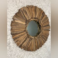 a mirror made out of sticks on top of a white rug with a circular hole in the middle