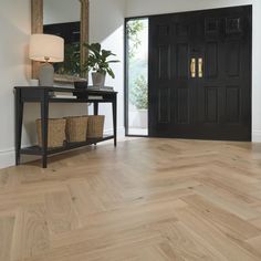 an entryway with wooden floors and black door, basket on the side table next to it