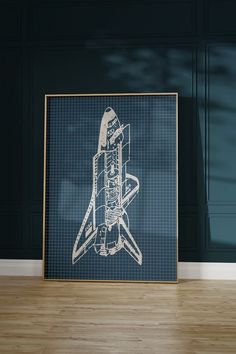 a drawing of a space shuttle is on the floor in front of a blue wall