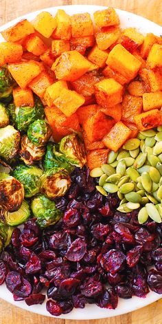 an assortment of vegetables on a plate with nuts and cranberries in the middle