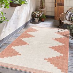 an orange and white area rug on a porch with potted plants next to it