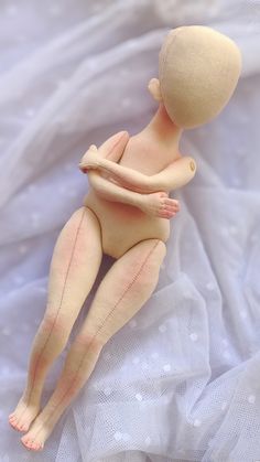 a naked doll laying on top of a white sheet